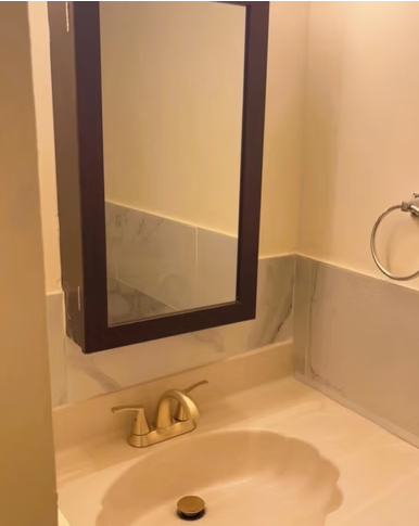 Powder room vanity with gold faucet and clean mirror