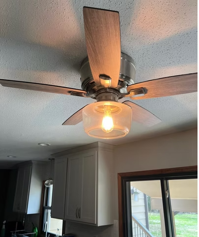 Ceiling fan with a glowing clean glass light fixture in a kitchen